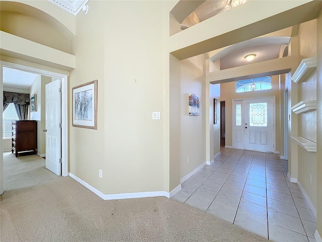 carpeted foyer featuring a towering ceiling