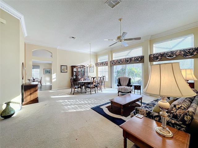 carpeted living room with ceiling fan with notable chandelier, a high ceiling, a textured ceiling, and crown molding