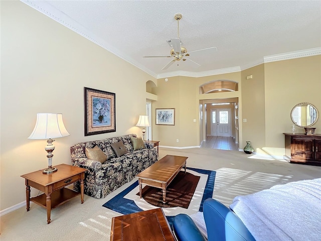 carpeted living room featuring a textured ceiling, ceiling fan, and ornamental molding