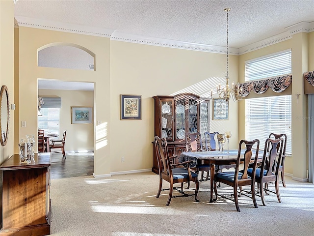 carpeted dining space with ornamental molding, a textured ceiling, and a chandelier