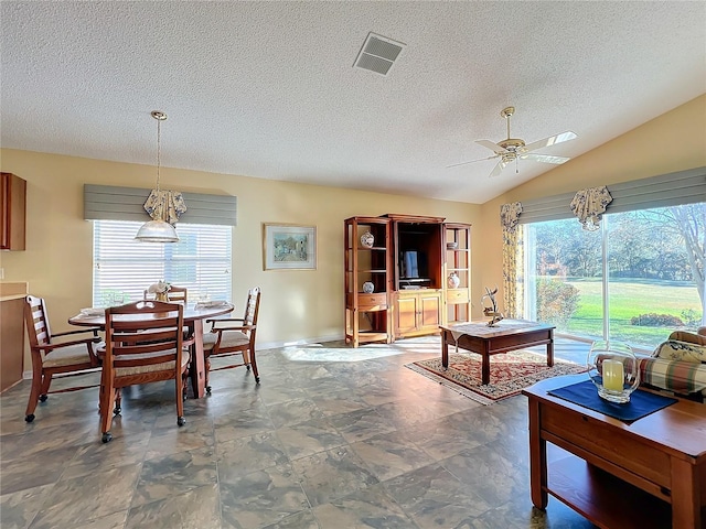 dining area featuring a textured ceiling, a wealth of natural light, ceiling fan, and lofted ceiling