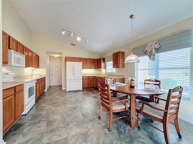 dining space with a textured ceiling, vaulted ceiling, and sink