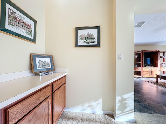 hall with light carpet and a textured ceiling