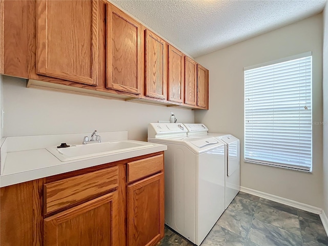 laundry area featuring sink, a healthy amount of sunlight, cabinets, a textured ceiling, and washer and dryer