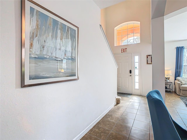 entryway with tile patterned flooring, a towering ceiling, and plenty of natural light