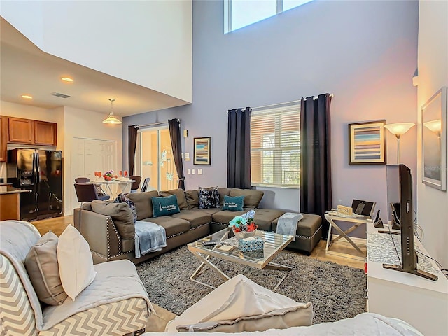 living room with a towering ceiling and light hardwood / wood-style floors