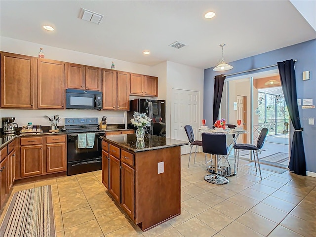 kitchen featuring light tile patterned flooring, dark stone counters, black appliances, hanging light fixtures, and a kitchen island