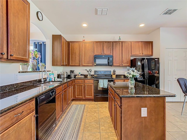 kitchen with a center island, black appliances, sink, dark stone countertops, and light tile patterned flooring