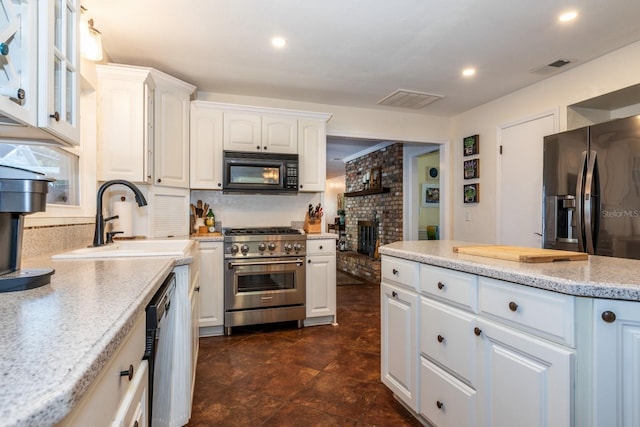 kitchen with decorative backsplash, appliances with stainless steel finishes, light stone countertops, sink, and white cabinets