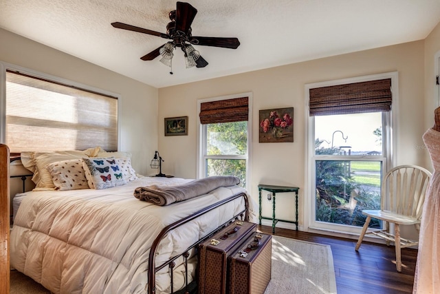 bedroom with a textured ceiling, dark hardwood / wood-style flooring, and ceiling fan