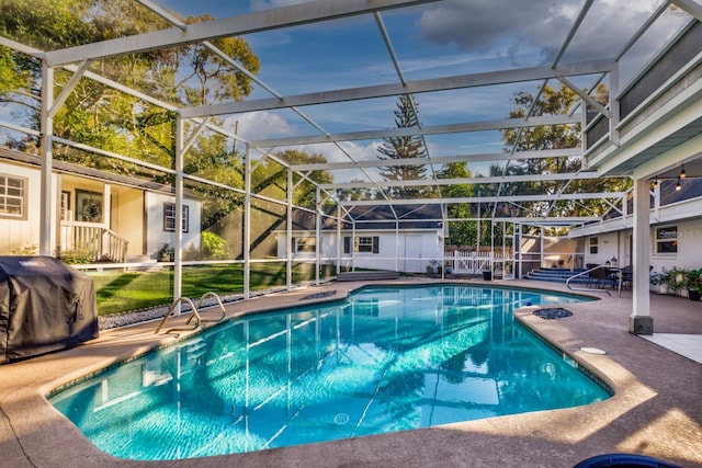 view of pool with a patio area, area for grilling, and glass enclosure