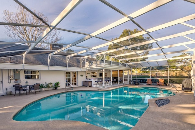 pool at dusk with a lanai, a patio area, and electric panel