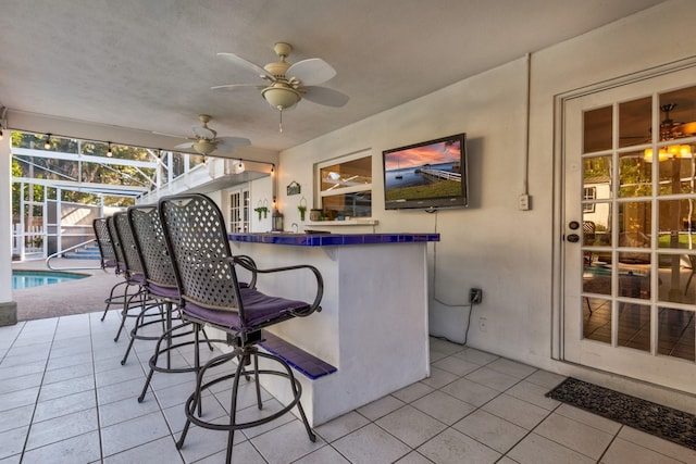 view of patio / terrace with a bar, ceiling fan, and a lanai