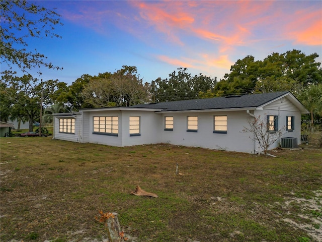 property exterior at dusk with a yard and central air condition unit