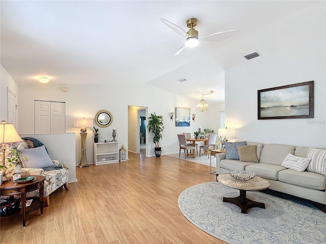 living room featuring light hardwood / wood-style floors, lofted ceiling, and ceiling fan with notable chandelier