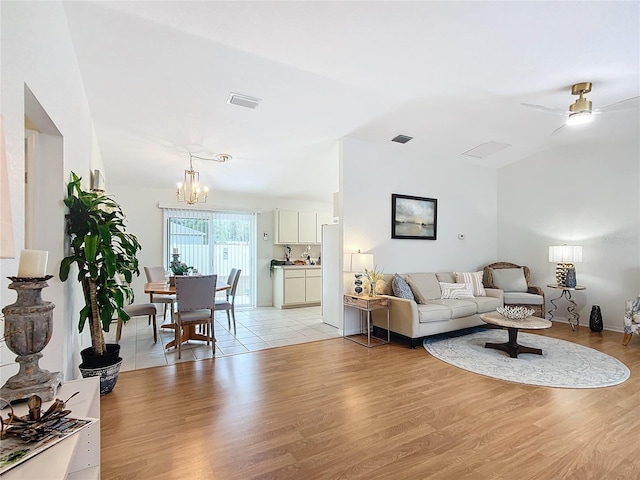 living room with light wood-type flooring and ceiling fan with notable chandelier