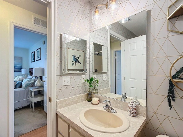 bathroom with hardwood / wood-style floors, vanity, and tile walls