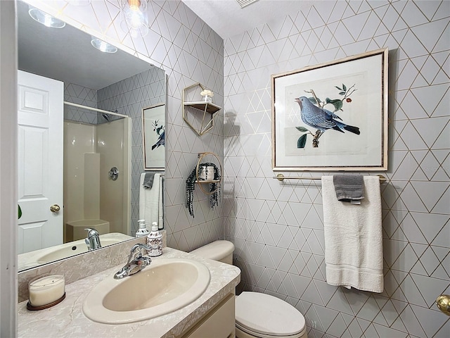 bathroom with a shower, tile walls, toilet, and vanity