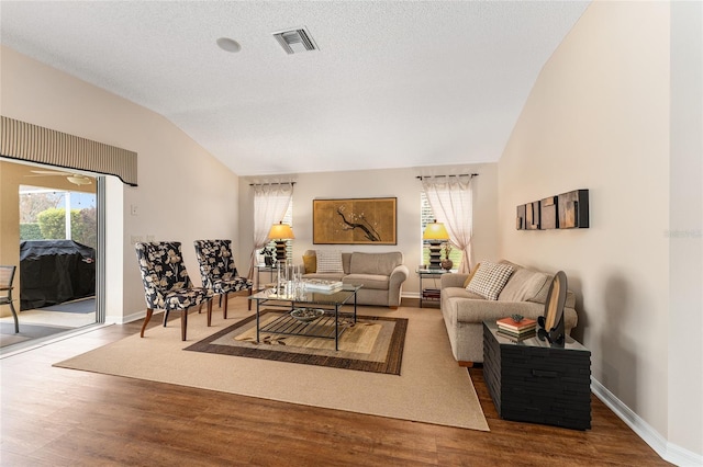 living room featuring vaulted ceiling, a textured ceiling, and hardwood / wood-style flooring