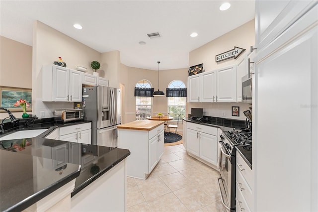 kitchen with white cabinets, butcher block countertops, appliances with stainless steel finishes, and tasteful backsplash