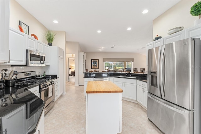 kitchen featuring white cabinets, appliances with stainless steel finishes, wooden counters, sink, and kitchen peninsula