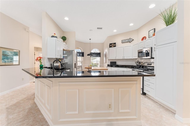 kitchen featuring light tile patterned flooring, appliances with stainless steel finishes, white cabinets, and a center island