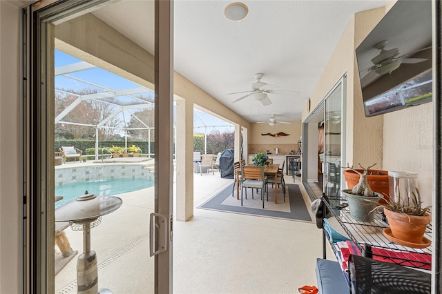 view of patio featuring ceiling fan and glass enclosure