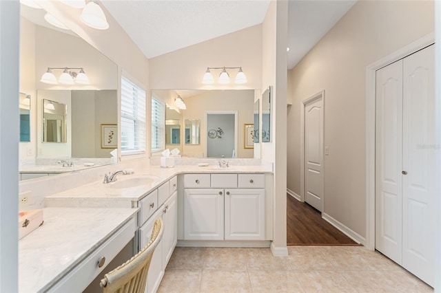 bathroom with tile patterned flooring, vanity, a textured ceiling, and vaulted ceiling