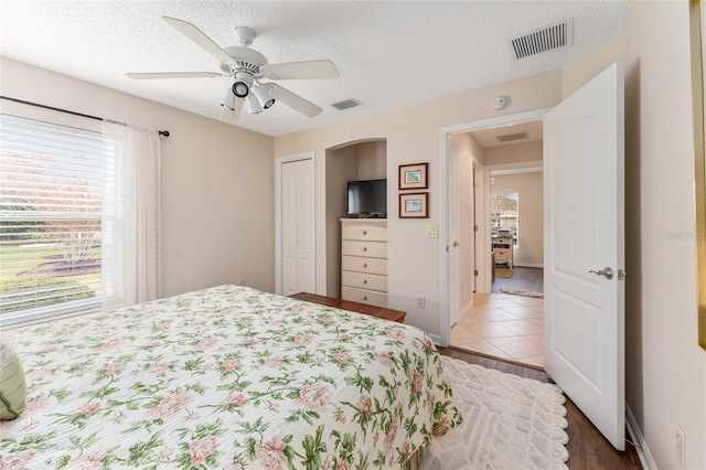 bedroom featuring a textured ceiling, ceiling fan, a closet, and hardwood / wood-style floors