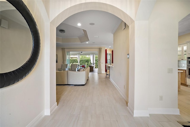 hallway featuring a tray ceiling and ornamental molding