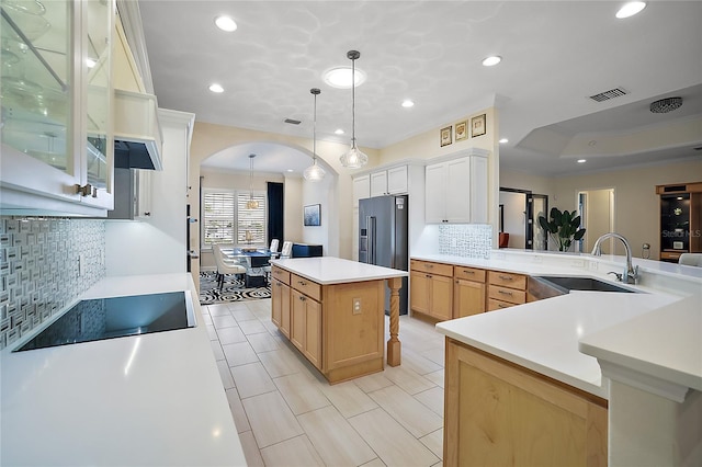 kitchen with backsplash, white cabinets, black appliances, sink, and a kitchen island