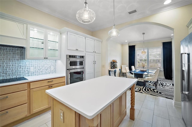 kitchen with light tile patterned floors, appliances with stainless steel finishes, tasteful backsplash, a kitchen island, and white cabinetry