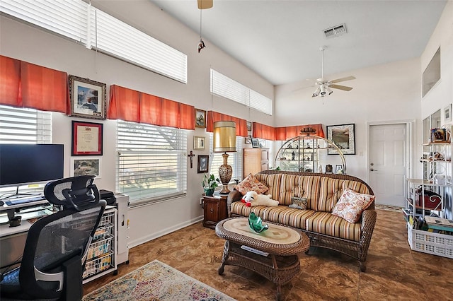 living area with ceiling fan, a high ceiling, visible vents, and baseboards