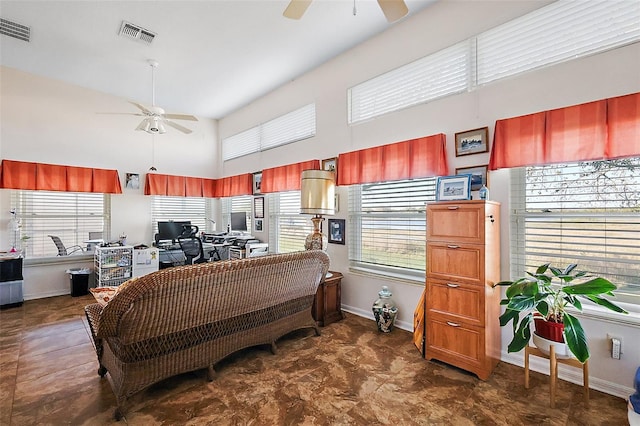 living area with a ceiling fan, visible vents, and a high ceiling