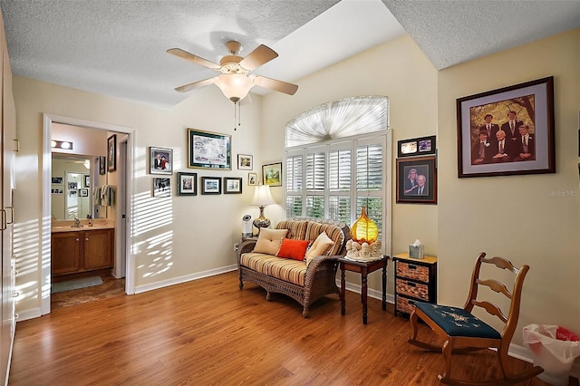 sitting room with ceiling fan, a textured ceiling, baseboards, and wood finished floors