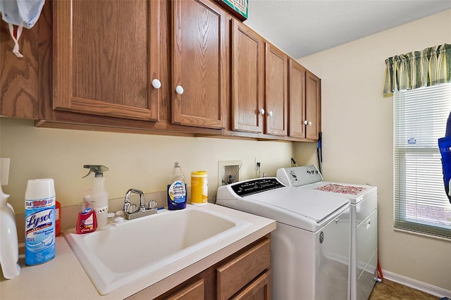 laundry room featuring baseboards, cabinet space, a sink, and washing machine and clothes dryer