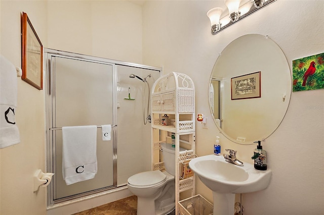 bathroom featuring toilet, a shower stall, and a sink