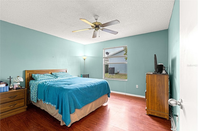 bedroom featuring dark wood-type flooring, a textured ceiling, and ceiling fan