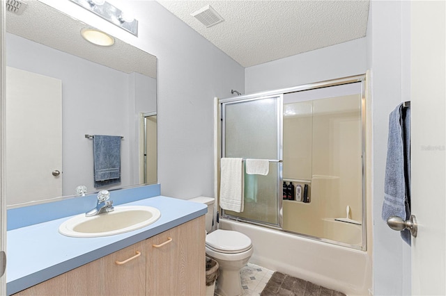 full bathroom featuring toilet, a textured ceiling, vanity, and shower / bath combination with glass door