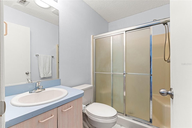 bathroom with a textured ceiling, an enclosed shower, vanity, and toilet