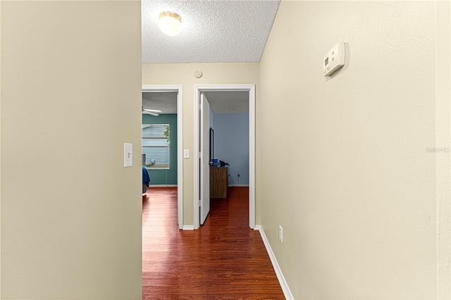 corridor with a textured ceiling and dark hardwood / wood-style flooring