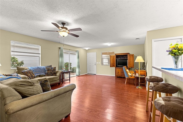 living room featuring ceiling fan, a textured ceiling, and dark hardwood / wood-style floors