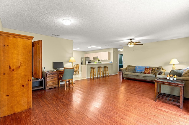 living room featuring hardwood / wood-style flooring, a textured ceiling, and ceiling fan