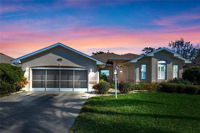 ranch-style home featuring a garage and a lawn