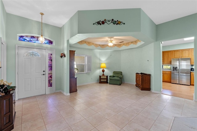 entrance foyer with ceiling fan, a towering ceiling, and light tile patterned flooring