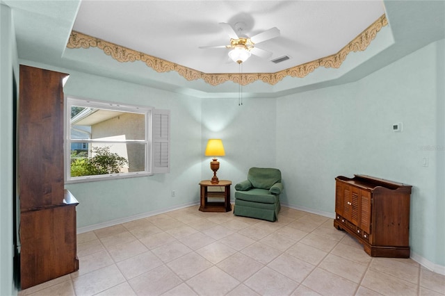 sitting room with ceiling fan, light tile patterned floors, and a raised ceiling