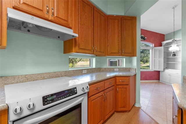 kitchen featuring light tile patterned floors, a wealth of natural light, decorative light fixtures, and stainless steel electric range