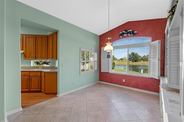 unfurnished dining area featuring lofted ceiling, a water view, and light tile patterned flooring