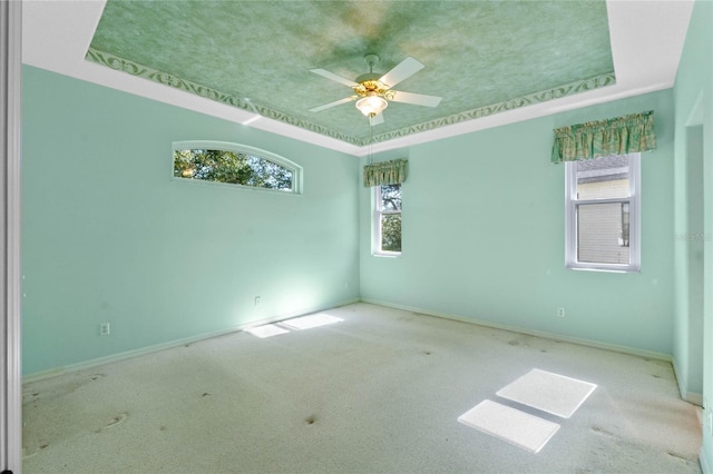 spare room featuring ceiling fan, a tray ceiling, and light carpet