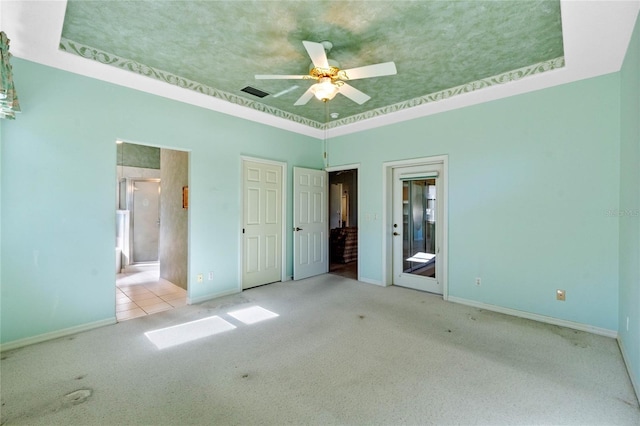 unfurnished bedroom with ceiling fan, light carpet, a tray ceiling, and crown molding